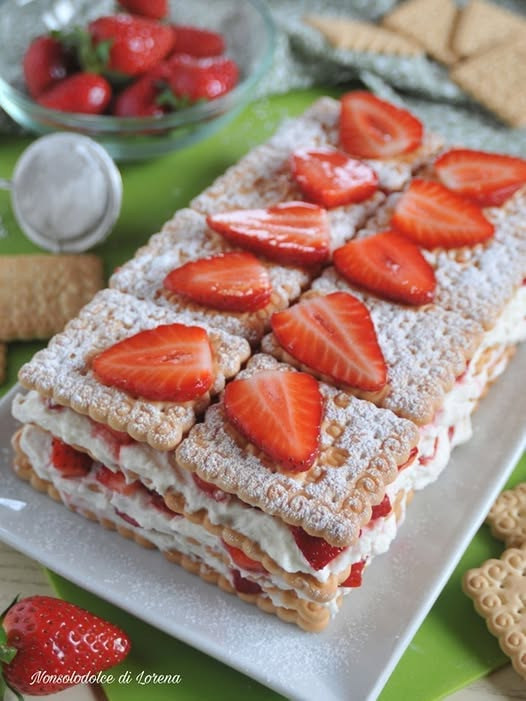 Dolce rettangolare a strati di biscotti, crema bianca e fragole